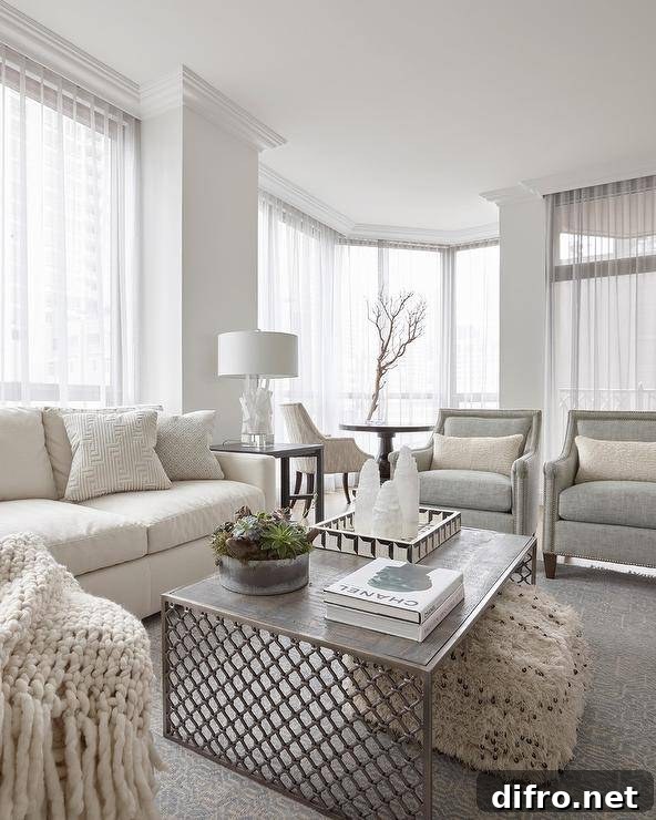 Transitional living room with ivory sofa, gray accent chairs and a textured ottoman under the coffee table.