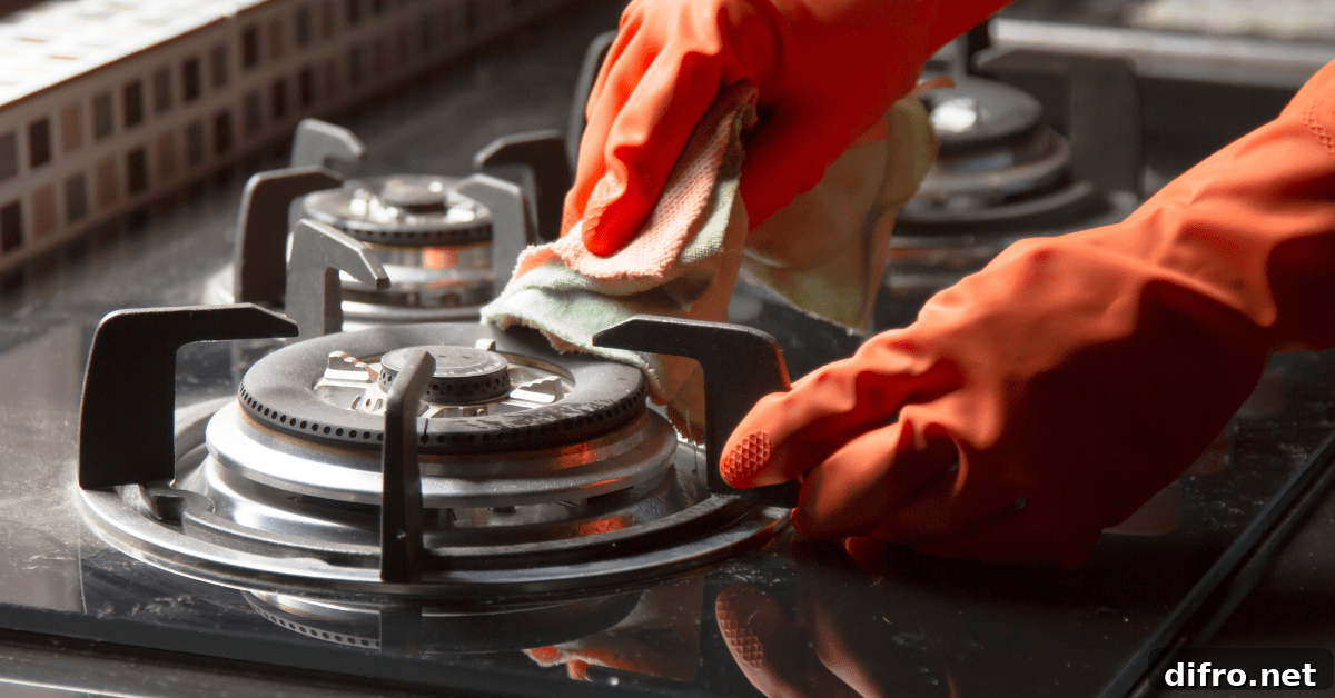 A person wearing orange gloves scrubbing down stove grates.