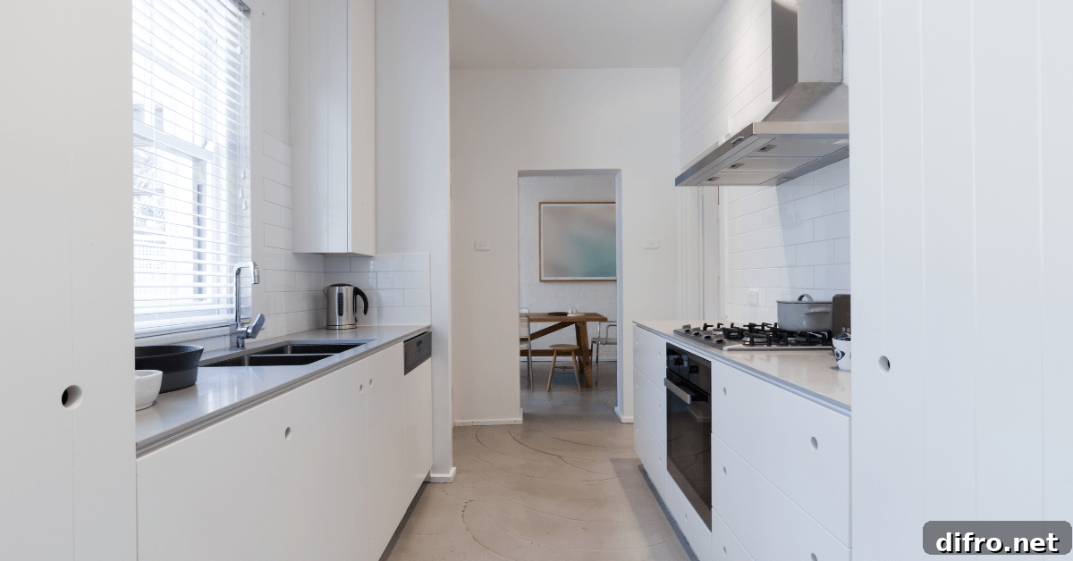 White galley kitchen with light hardwood flooring.