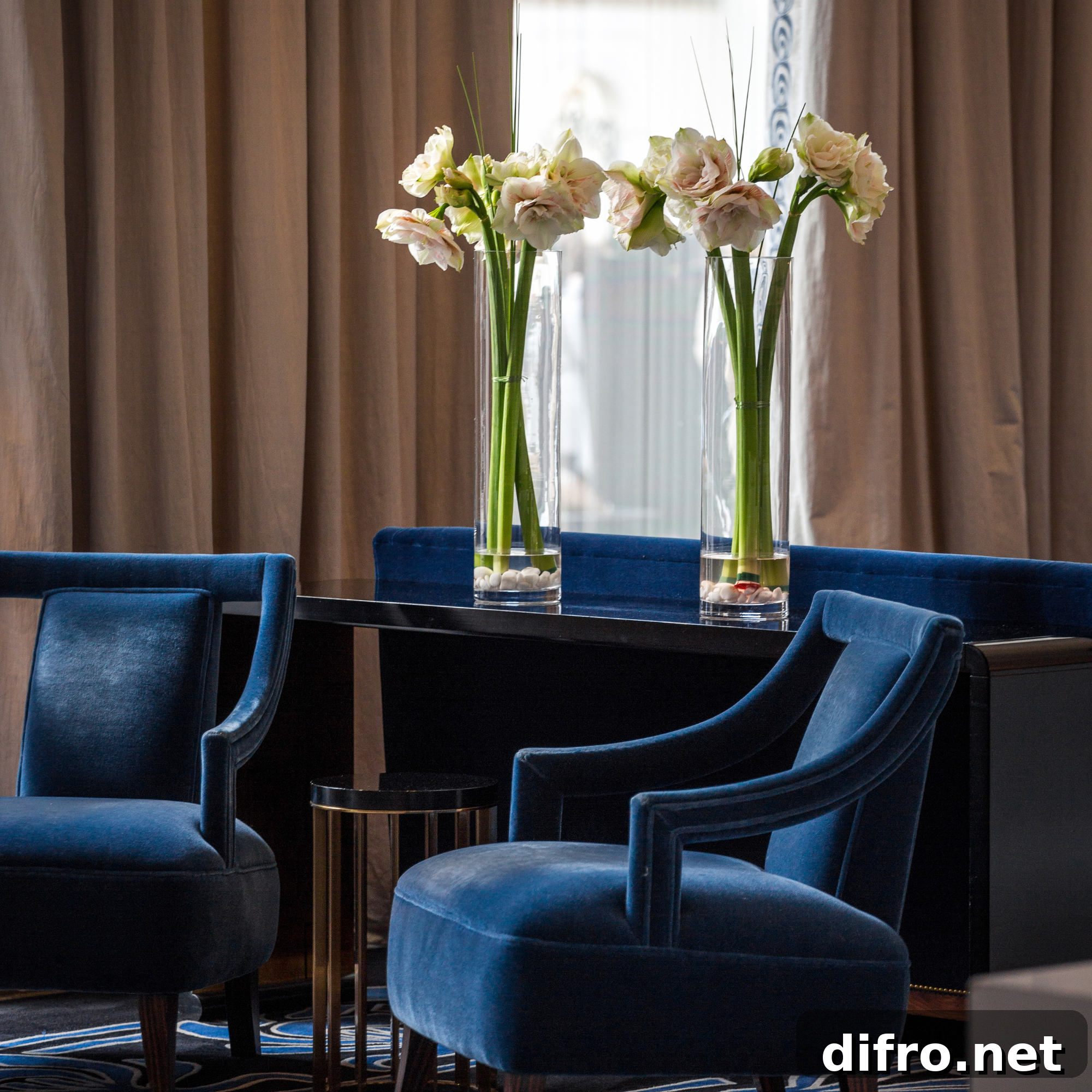 Royal blue chairs in a bold living room flanked by follows in vases.