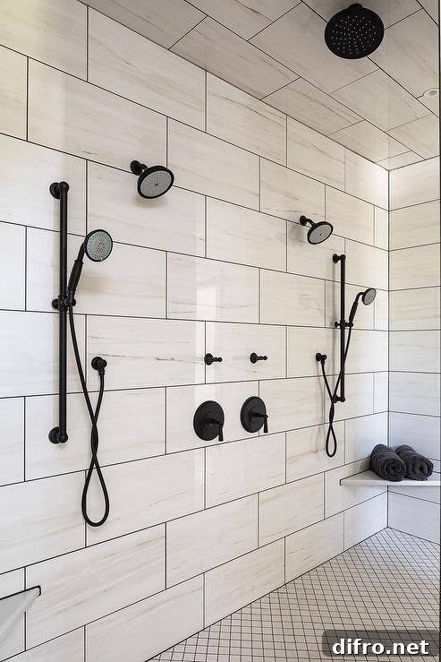 White lattice floor tiles accent a walk-in shower fitted with his and hers oil rubbed bronze shower kits mounted to large white offset wall tiles, a bronze rain shower head, and a corner floating bench.