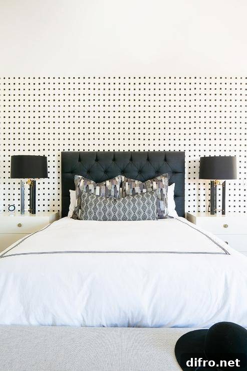 Black and white wallpaper complements a black tufted headboard and white lacquer nightstands illuminated by black lamps.