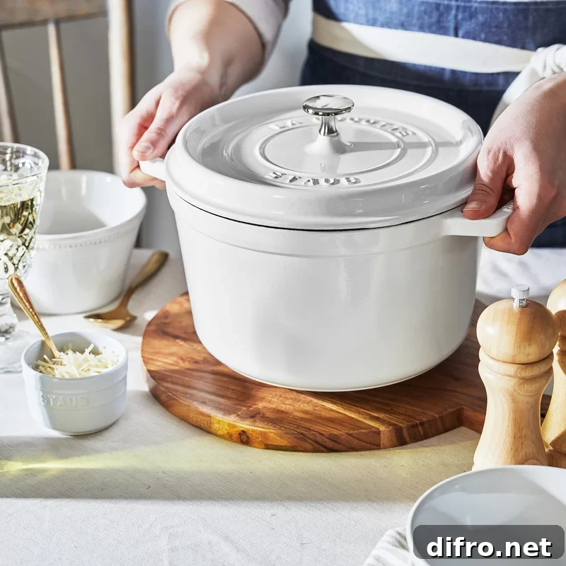 Staub white cast iron dutch oven on a wood trivet