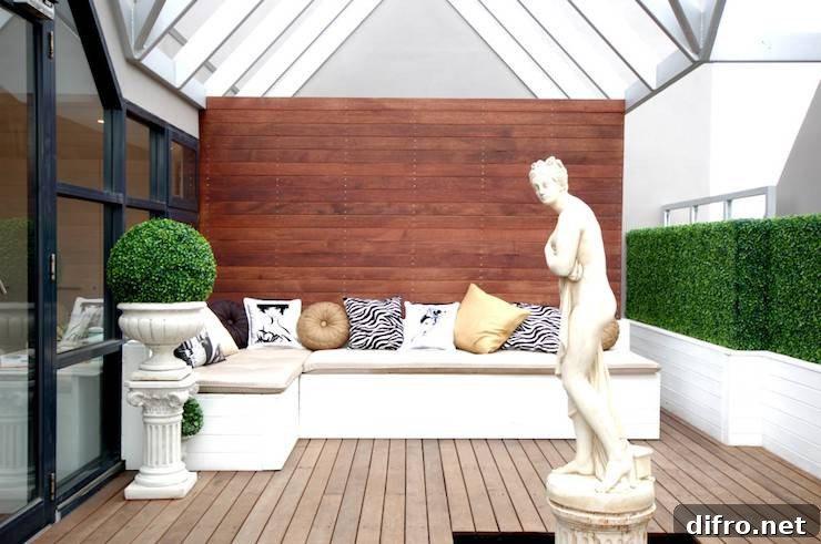 Contemporary patio features vaulted glass ceiling over L shaped built-in seating accented with patterned pillows and classical statue in center of space.