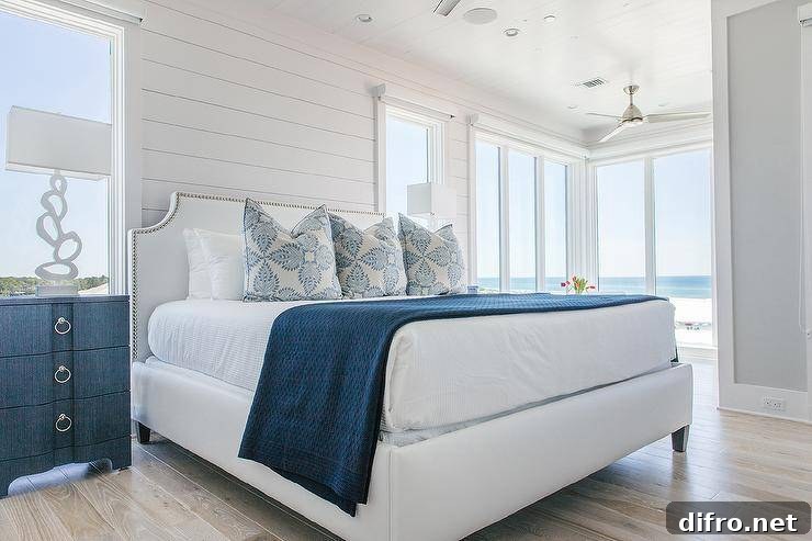 White and blue cottage bedroom features Bungalow 5 Bardot 3 Drawer Dressers placed flanking a white French bed dressed in white and blue bedding complemented with white and blue pillows. The bed sits against a white shiplap wall between windows.