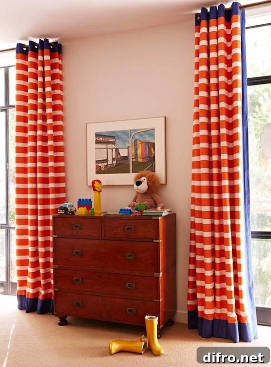Blue and orange boy's bedroom with vintage campaign style chest flanked by windows covered in floor to ceiling orange and white striped grommet drapes.
