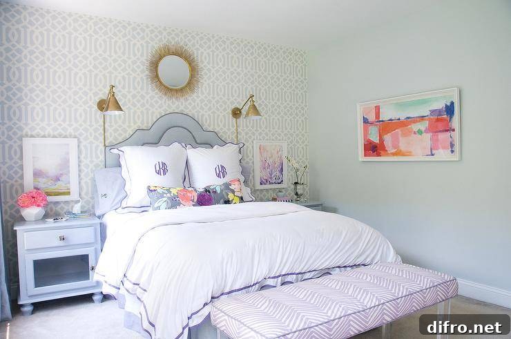 Soft pastel colors and a classic style will keep this girls room timeless. Trellis wallpaper walls with gold accented mirror and Boston Functional Library Wall Lights create a chic vibe across the wall and allow a curved purple headboard and monogrammed bedding to be the center of attention. Blue nightstands are decorated with floral arrangements and accessories while framed wall art is featured over them. A purple zebra bench with lucite legs is seated at the end of this luxe bed adding a dimensional and fun pattern!
