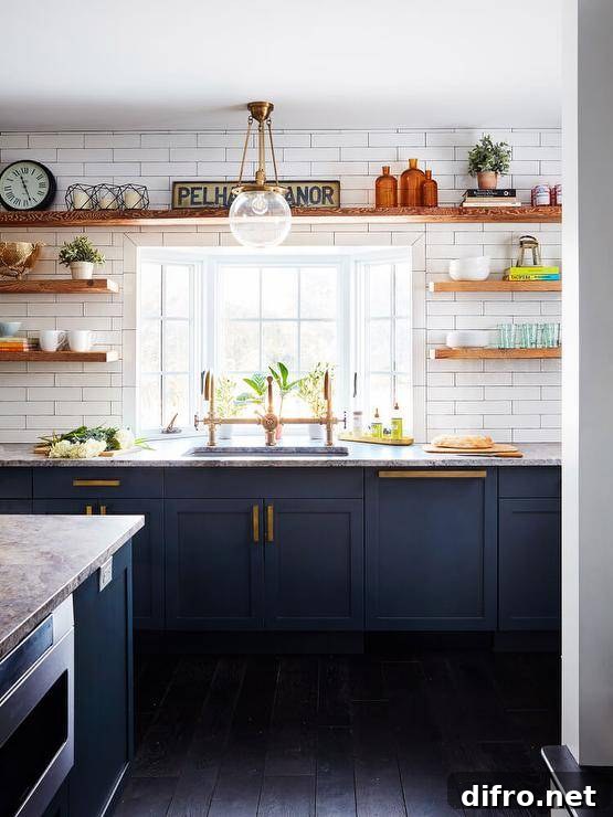 Brown wooden floating shelves are fixed to white subway wall tiles on either side of and above a window located above a sink with a brass dual deck mount faucet.