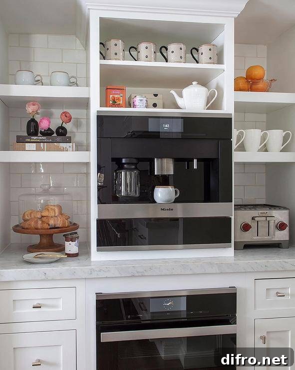 White floating shelves are stacked against white subway backsplash tiles over white cabinets topped with a honed marble countertop and on either side of a built-in Miele coffee machine.