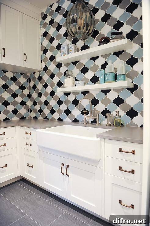 Gray blue and black Moroccan laundry room wall tiles create a stunning display surrounding white shaker cabinets with brass pulls and gray quartz countertops.