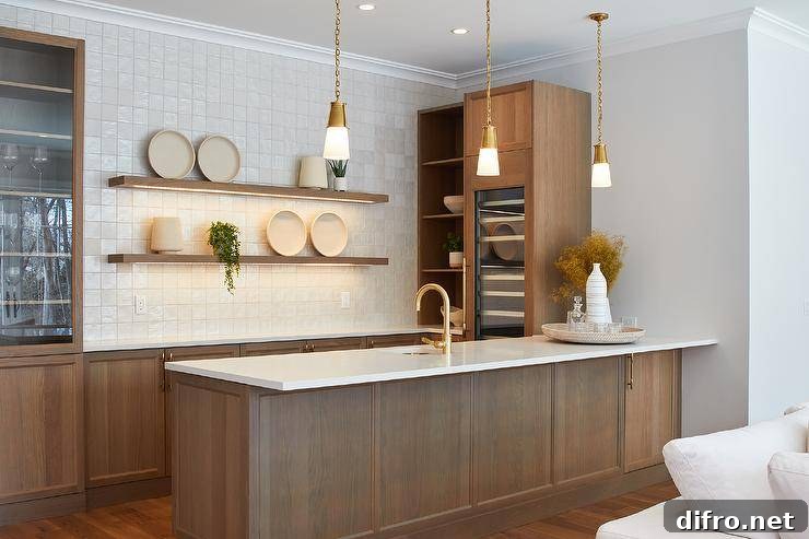 Lighted oak floating shelves are stacked against light gray grid backsplash tiles over oak wet bar cabinets adorned with brass hardware.