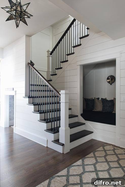 Recessed into a wall, a reading nook is fitted with a built-in seat topped with a black cushion located against a white board and batten trim.
