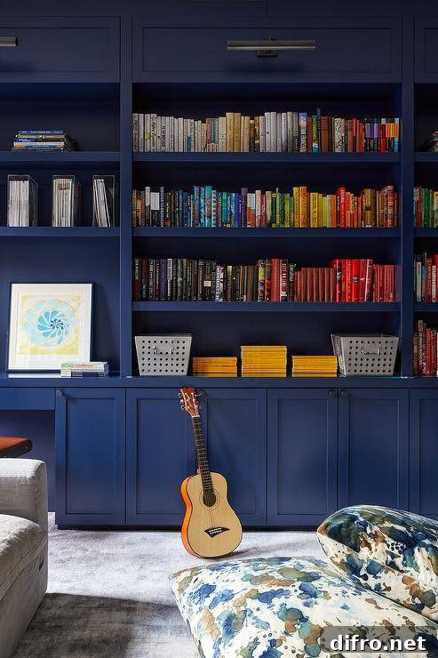 Home office features bold blue bookshelves with books organized by color