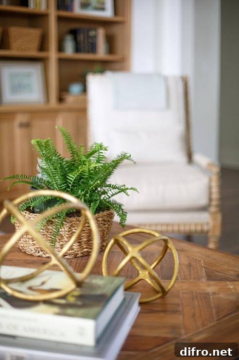A beige spindle chair stands faces a wood top coffee table adorned with decorative brass spheres.