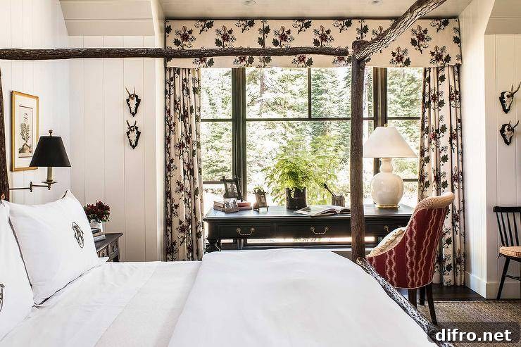 Elegant cottagecore bedroom work space features a red desk chair placed at a black French desk topped with a white gourd lamp and positioned in front of windows dressed in floral curtains with a matching valance.