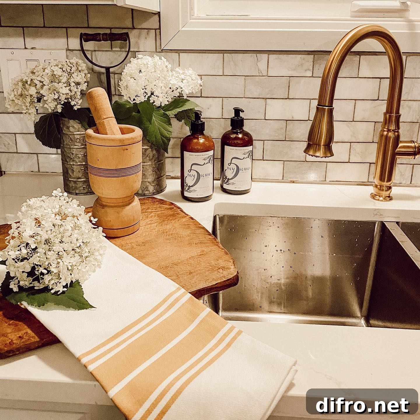 kitchen sink with gold faucet tea towel hydrangea on rustic wood cutting board