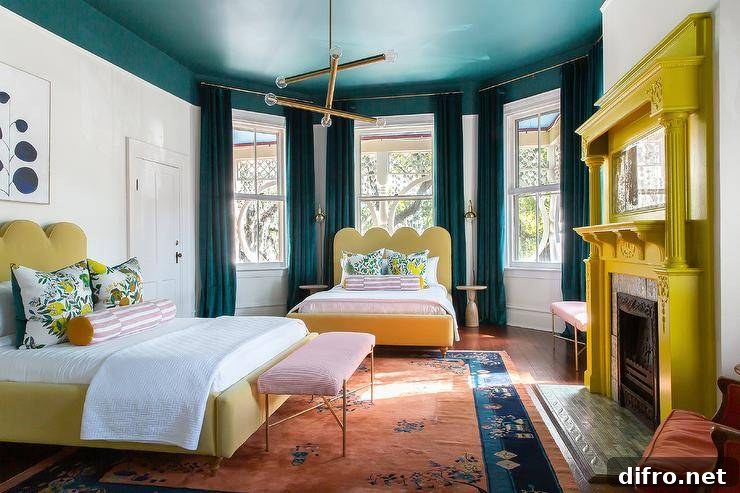 Contemporary bedroom features a yellow painted fireplace mantel with mosaic tiles, a yellow scalloped headboard with lemon print pillows and a pink stripe bolster pillows under a bay window with peacock blue velvet curtains, a matching bed under art and a peacock blue painted ceiling.
