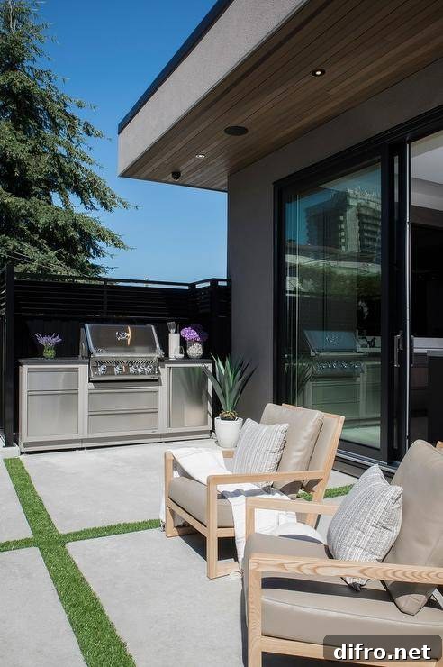 Stylish patio features stainless steel mini bbq kitchen, blond teak outdoor chairs with taupe cushions atop concrete pavers.