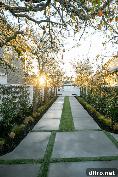 A row of trees lines a large concrete walkway accented with concrete pavers and grass pavers.
