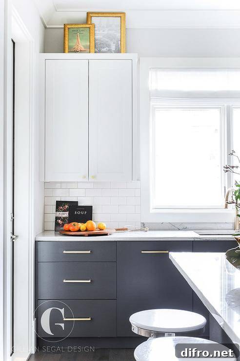 Transitional white and gray kitchen with two toned cabinets feature white upper shaker cabinets and gray lower flat front cabinets with brass pulls.