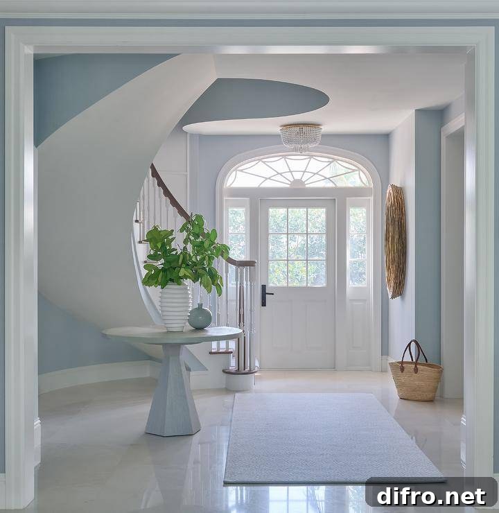 A white front door with sidelights beneath an arched transom window opens to an entry with a round oak table.