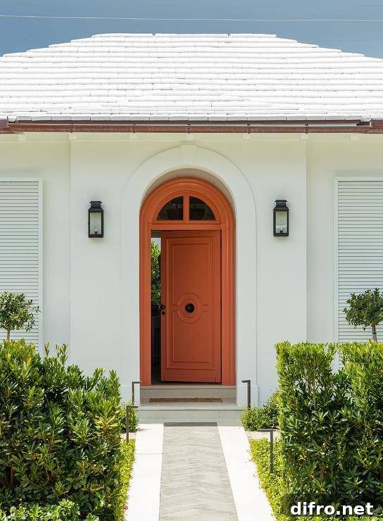 Bungalow features an orange front door illuminated by black lanterns.
