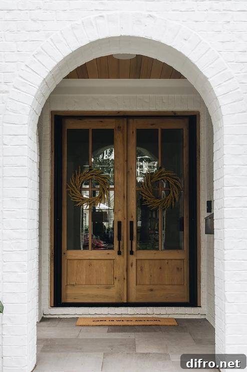 White painted brick home features wood and glass double front doors.