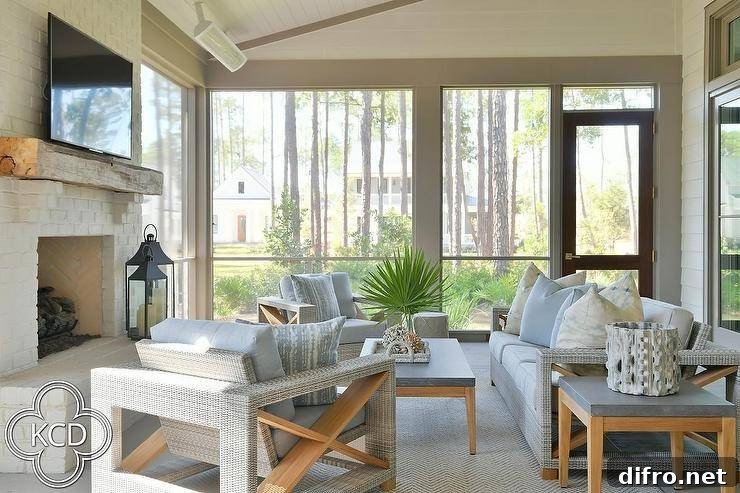 Welcoming gray sunroom with wicker and teak seating, rug and fireplace
