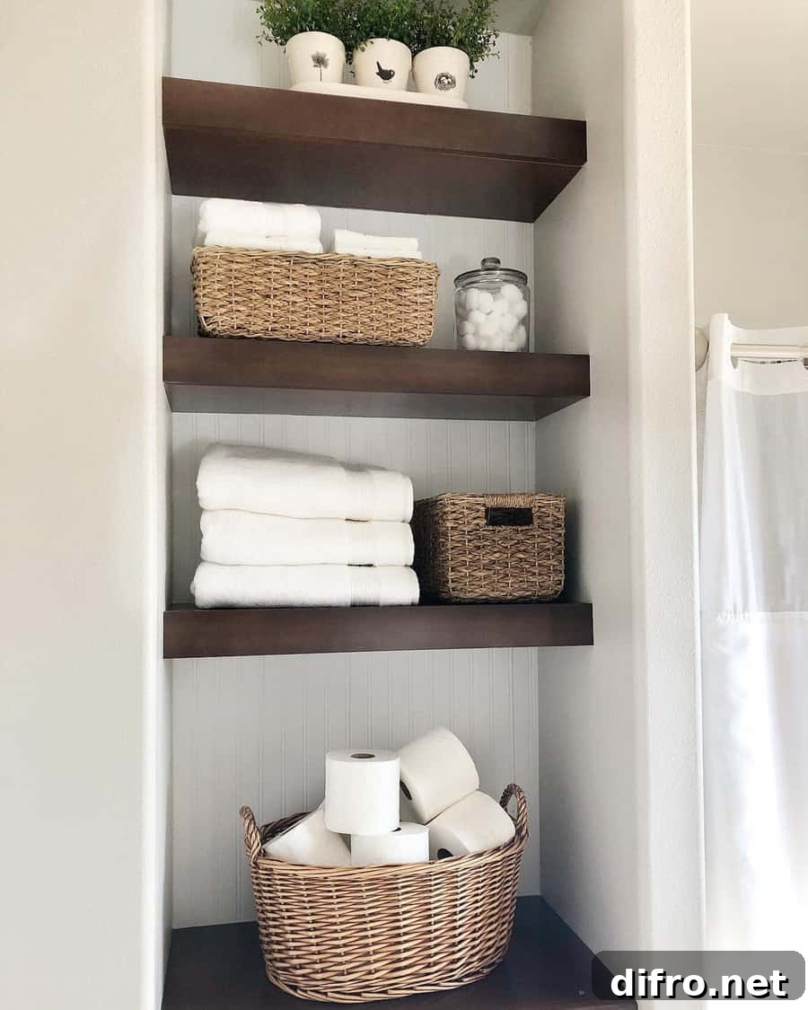open shelving closet in bathroom with wood shelves beadboard backing baskets folded white towels toilet paper