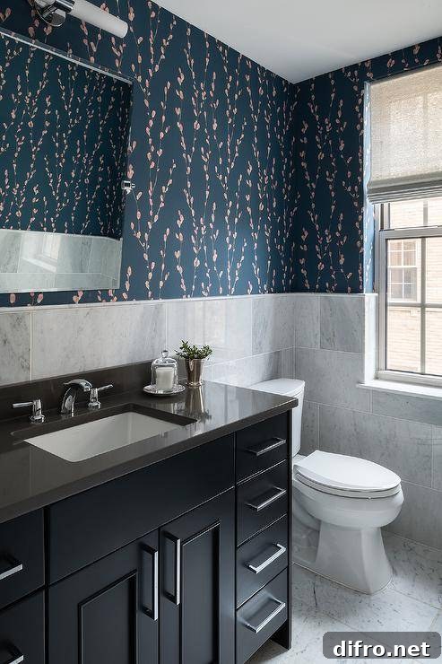 Gray marble offset wall tiles cover half of bathroom walls finished with Harlequin Salice Wallpaper, as a pivot mirror is mounted above a black washstand donning polished nickel pulls and a polished nickel faucet fixed to a black quartz countertop.