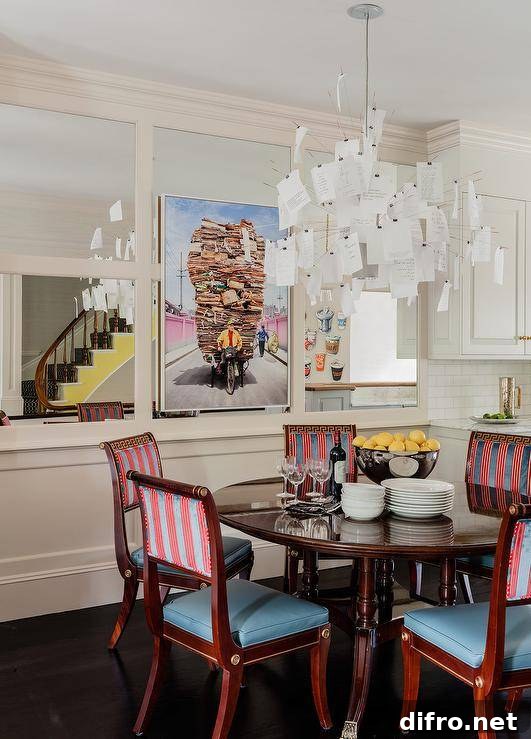 Paper notes chandelier illuminates a French dining table fitted with red and blue French chairs in an eclectic dining room design.