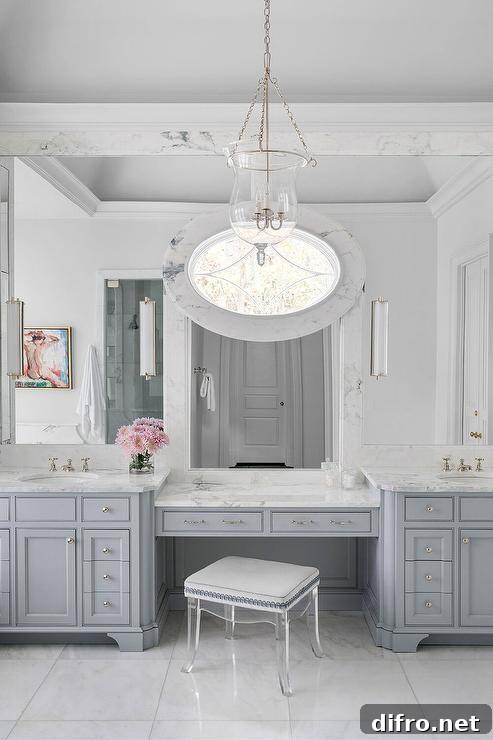 A French lucite stool stands in front of a gray makeup vanity topped with white and gray marble.