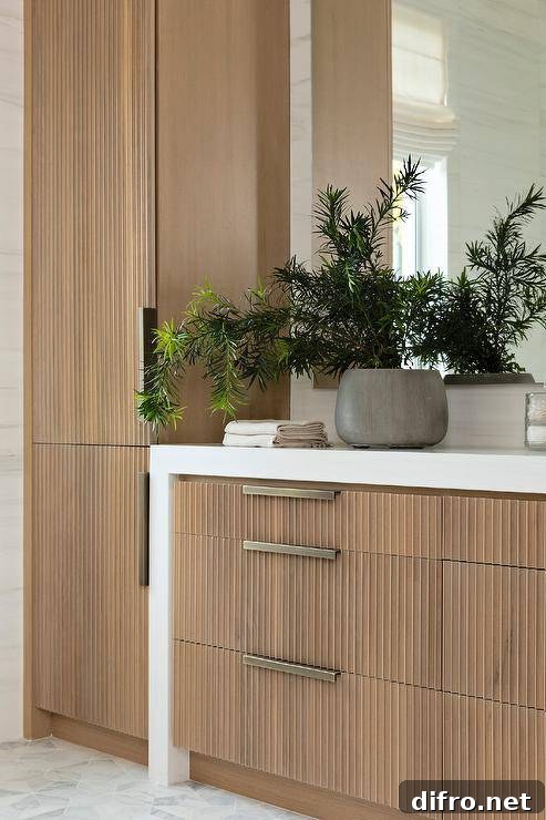 Bathroom features a reeded washstand with white quartz waterfall edge and brass hardware mosaic marble floor tiles.