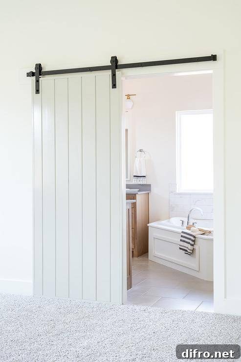 A white plank barn door on rails opens to a bathroom.
