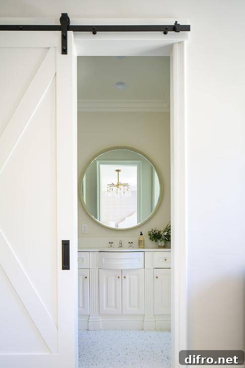 A white barn door on rails opens to an en suite bathroom.