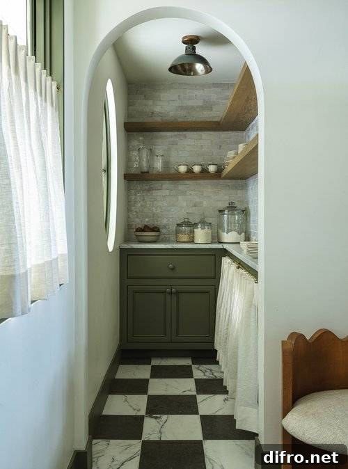 Kitchen features a small green walk in pantry with black and white marble checkered floor tiles and L shaped wooden shelves over gray marble offset backsplash tiles.