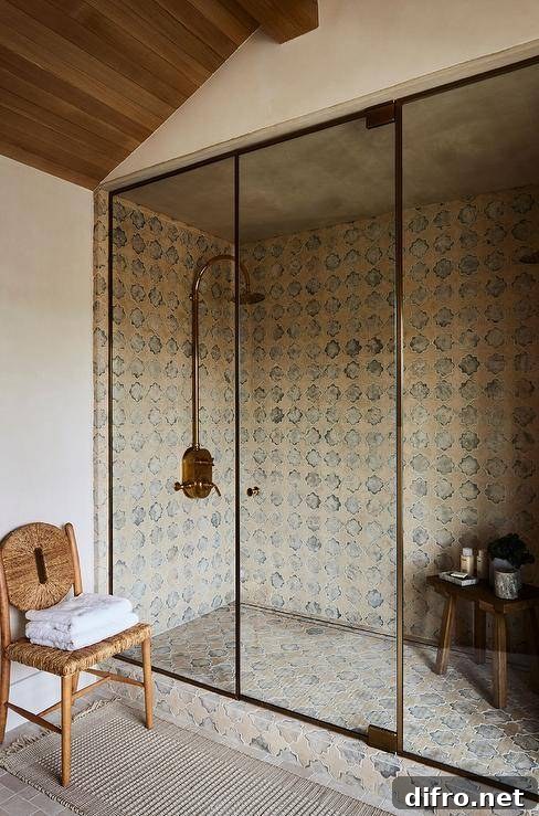 A walk in shower with a glass and brass enclosure boasts an eye-catching vintage brass shower kit mounted to Moroccan style surround tiles over matching floor tiles.