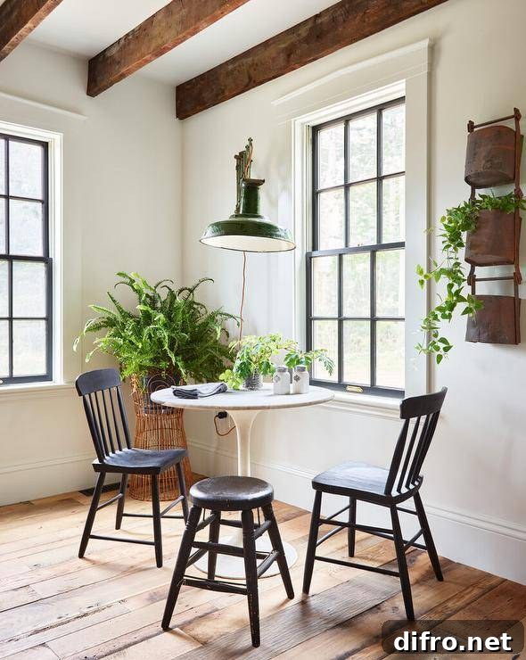Dining space features a green accordion style lantern that illuminates a marble tulip table with vintage black spindle chairs under wooden ceiling beams.