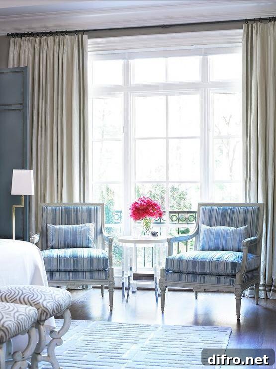 Master bedroom sitting area features gray French Louis Chairs with blue stripe cushions under a window with cream curtains.