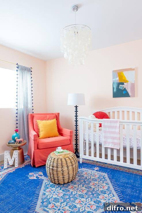 Orange and blue nursery with bright rug, woven pouf and hot pink accent chair beside a white crib.