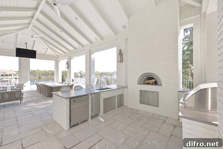Spacious covered patio features a white brick outdoor kitchen with custom pizza oven.