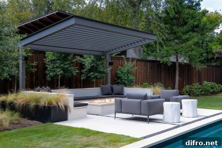 A two-post black pergola is fixed over a built-in u-shaped bench accented with black cushions and pillows and positioned at a concrete fire pit.