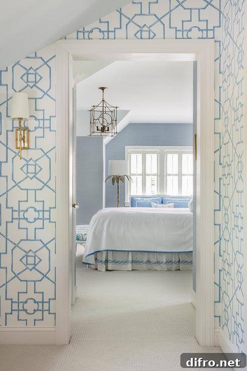 Blue bedroom walls are lit by a silver leaf floor lamp and a brass lantern hung in front of a bed covered in white and blue bedding with a white and blue bedskirt.