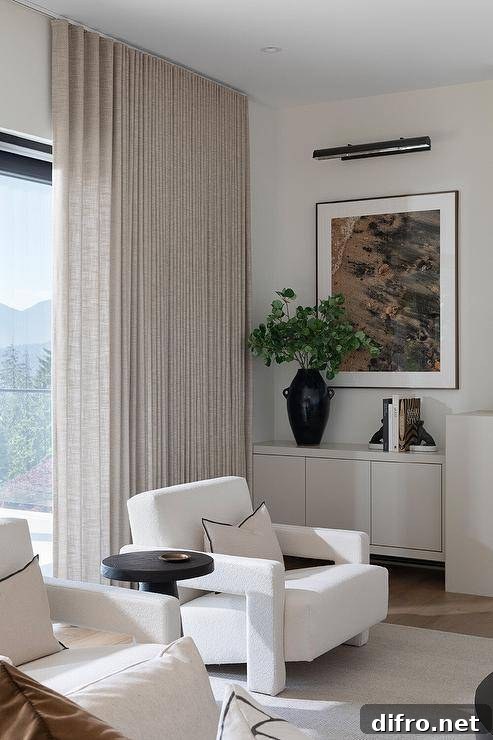 White boucle chairs with black and white pillows sitting on a white rug flanking a round black accent table.