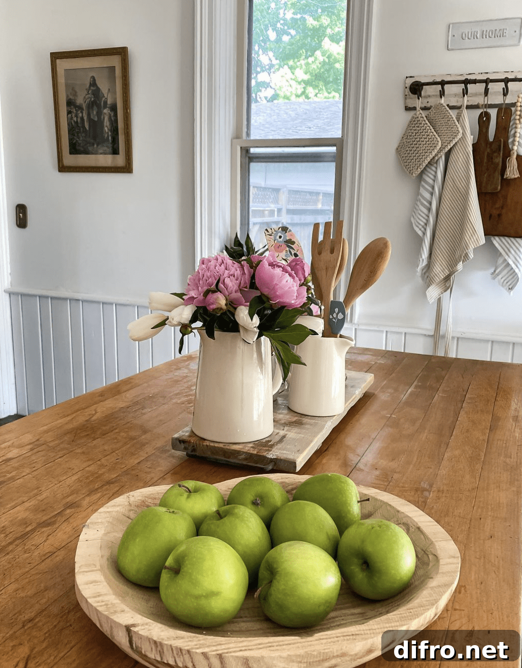 butcher block counter top with apples in wood bowl and flower arrangement