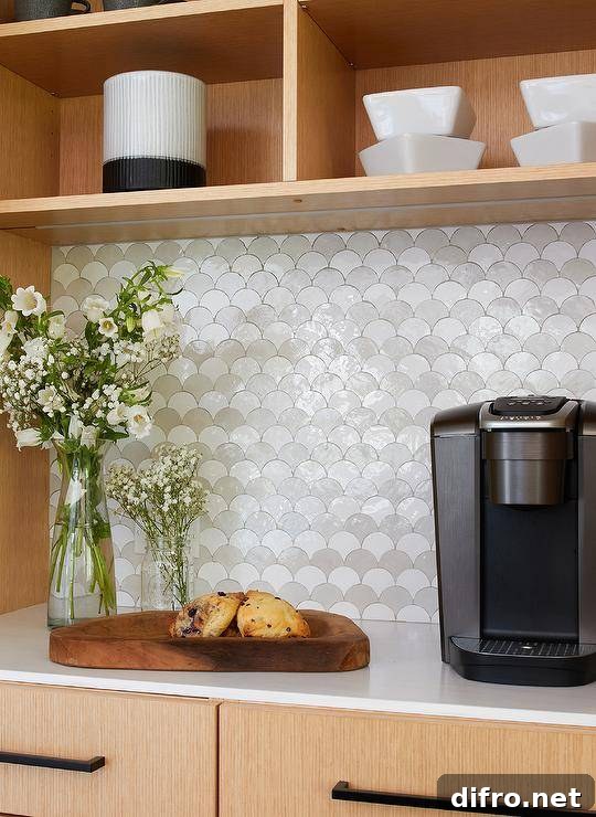 Kitchen features a coffee station with white and gray scale tiles under beige shelving.