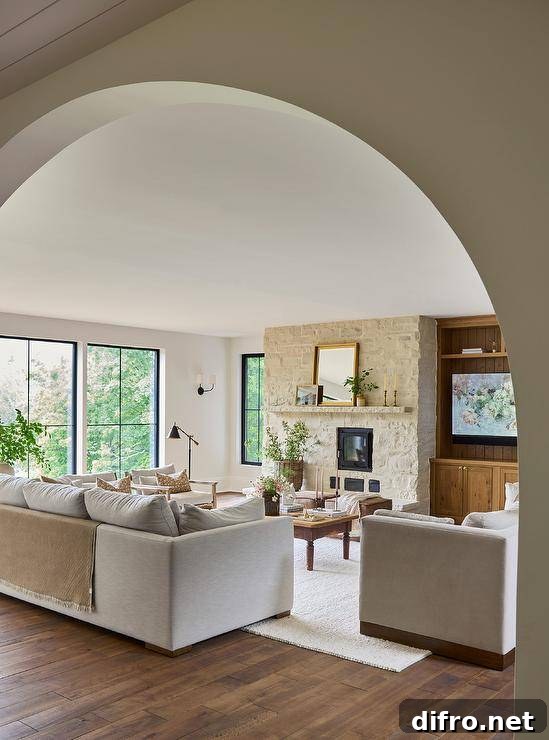 A white sofa sits on a white rug facing a farmhouse coffee table