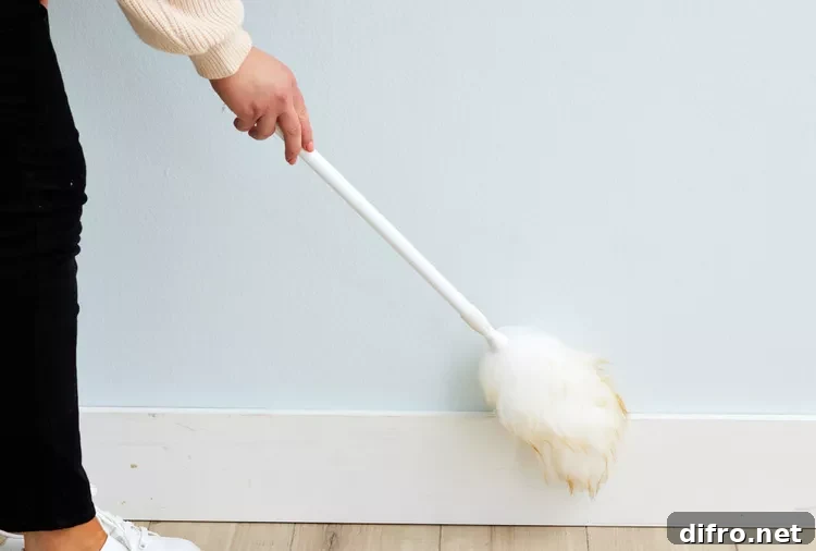woman dusting baseboards with duster