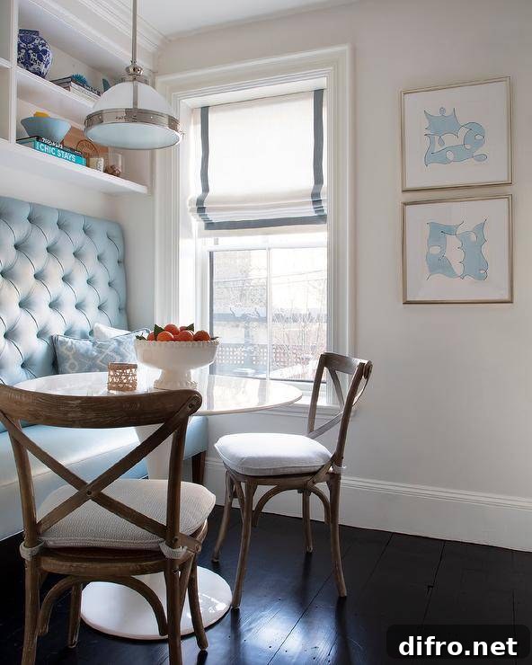 Chic white and blue keeping room with a round white tulip table and a turquoise tufted banquette bench.