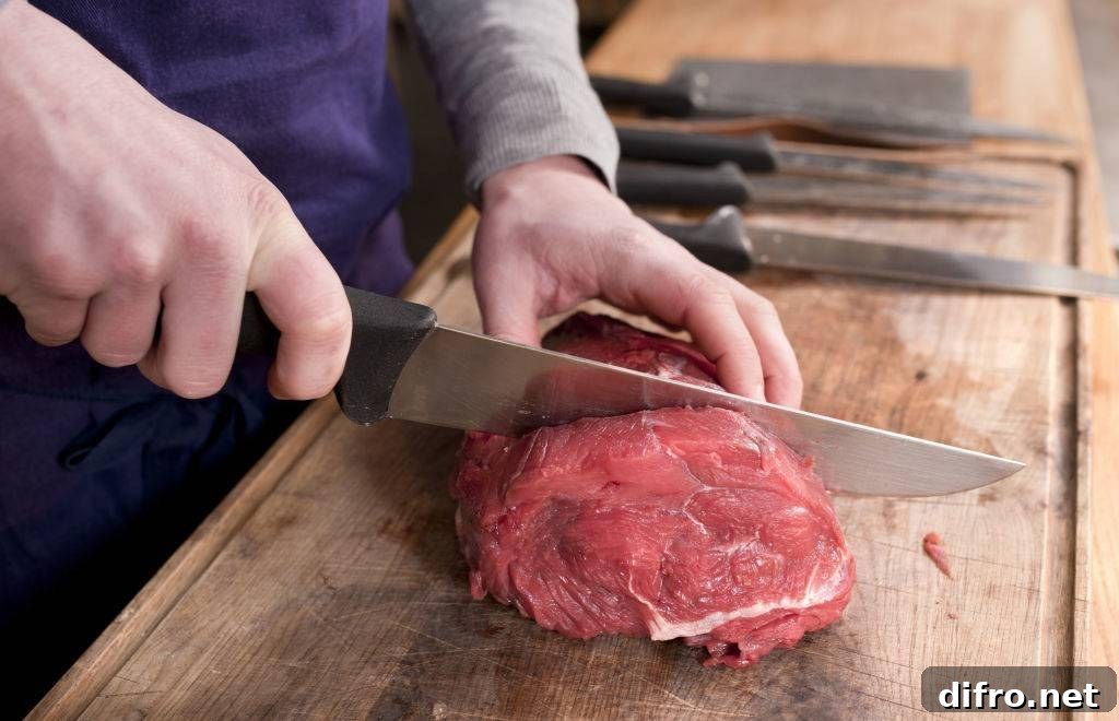 Close up shot of the hands of a butcher cutting a piece of meat.